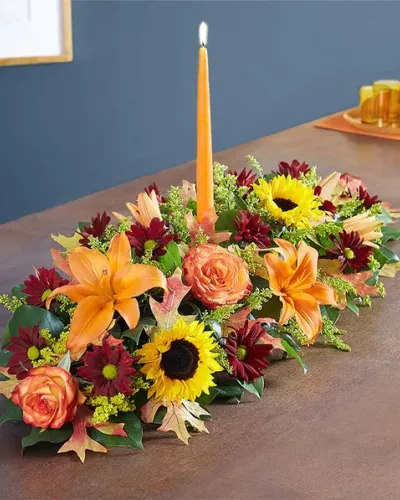 The rich beauty of the European countryside comes alive in our best-selling fall centerpiece. Crafted by our artisan florists, it’s filled with a gathering of fresh-picked blooms in brilliant colors and finished with an orange candle to warm hearts and homes.